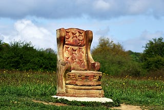 Ornately carved wooden chair in an empty field.