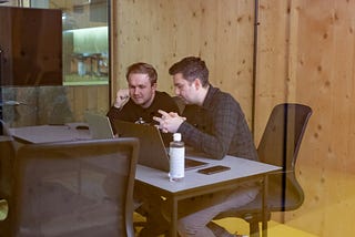 Two male co-workers looking at a computer in an office.