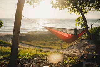 A person in a hammock with the sea in the background.