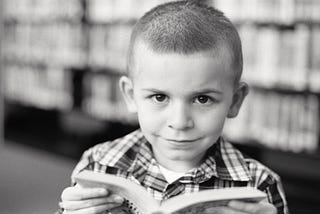 Photo of a small boy, reading.