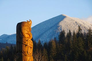 A totem pole stands in front of a mountain