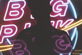 The shape of someone in front of neon bingo letters