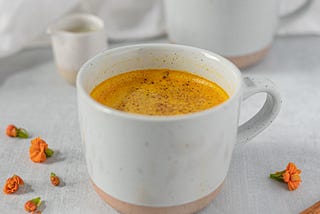 Golden milk, topped with connaom in a white mug