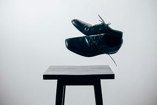 A pair of men’s shoes, floating in mid air above a small table
