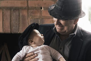 Middle-aged man smiling at the baby he is holding