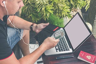 A guy with an open laptop counts the money in his wallet