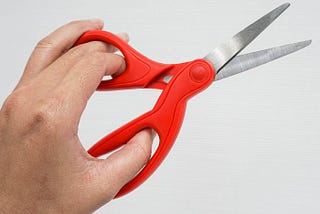 A left hand using scissors designed for the right hand.