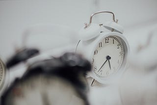 A single alarm clock in focus, amidst a larger collection of clocks