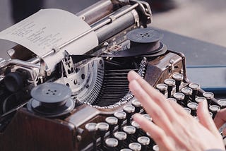 Person typing on antique typewriter.