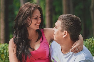 A woman sitting on a man’s lap, her arm around his neck.
