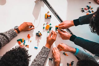 Picture of 3 people’s hands building and playing with Legos