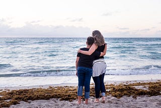 a mother and son at the beach, watching the waves.