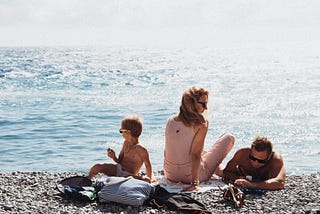 A mom and dad with their child on the beach.