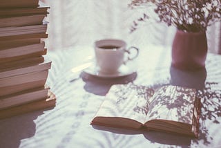 Calming scenery with an open book, vase and a cup of coffee
