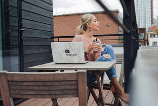 a woman sitting at a cafe table and computer drinking tea