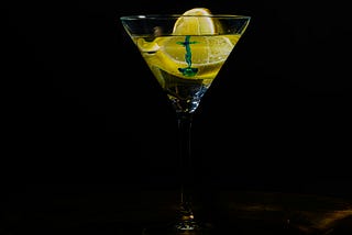 A lemon in clear liquid in a martini glass