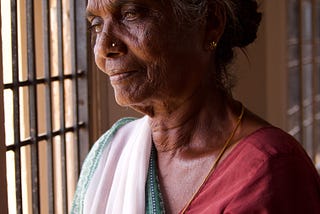 A woman looking out a window waiting for someone to return.