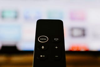 closeup of a tv remote control in front of a screen