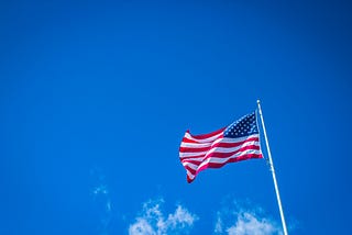 The American flag waving against a blue sky.