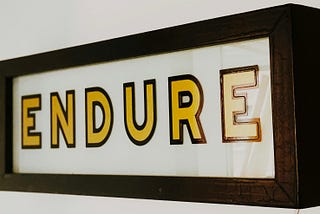 Wall sign that say “Endure” in gold coloured letters