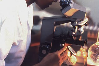 A Scientist in a lab coat looking in a microscope
