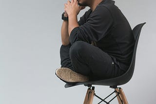 Man with beanie sitting cross legged on chair