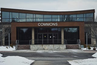 A community college building with the word “COMMONS” above the front door in a snowy landscape.