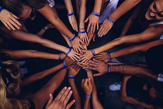 A bunch of people touching hands in a circle.