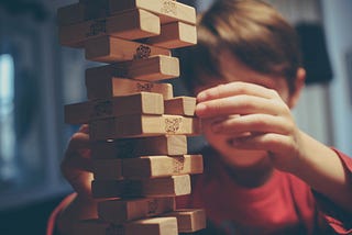 A young boy tries to balance cubes of woods to buid a castle