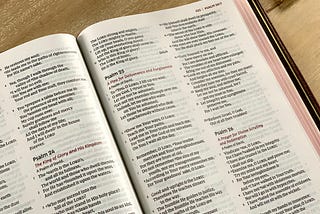 A Bible open to the Psalms. Psalm 24, 25, and 26 are visible on the page.