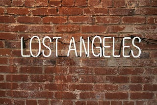 A picture of lit up words “lost Angeles” against a brick wall; a play of words to depict being lost