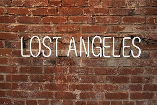 A picture of lit up words “lost Angeles” against a brick wall; a play of words to depict being lost