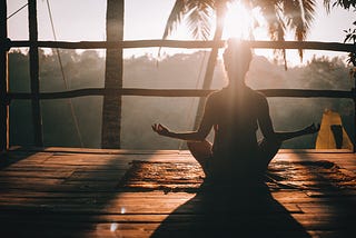 Une femme en position du lotus, face au soleil.