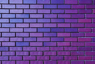 A section of brick wall in close-up in various hues of purple.