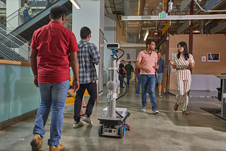A robot navigates between 4 people walking in an office space