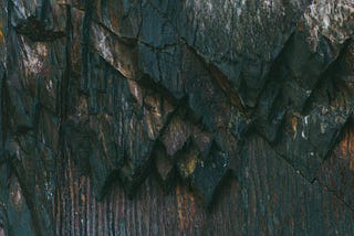 Human hand outstretched reaching up a cliff wall.