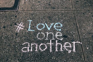 Love One Another written on sidewalk.