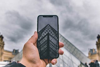 Man with a smartphone taking a photo of a building.