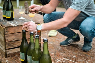 Person opening wine bottles with a hammer and nails