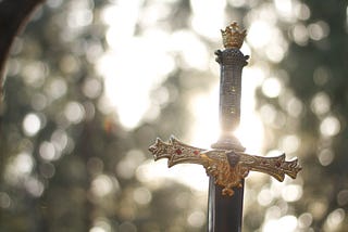 [Image of a sword in a forest in the sunlight]