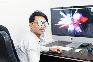a young entrepreneur sitting at his desktop and looking back at camera