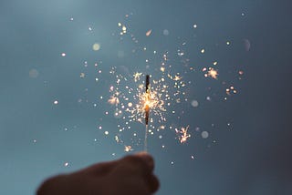 A hand holding a sparkler to the sky