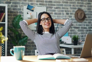 Portrait of happy young woman relaxing in office with cup of coffee.