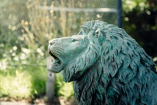 a stone lion, roaring in profile.