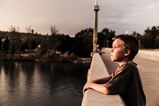 Kid thinking on a bridge