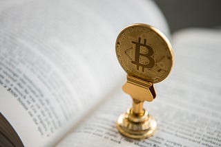 En bitcoin-dekoration som står på sidorna av en öppen bok