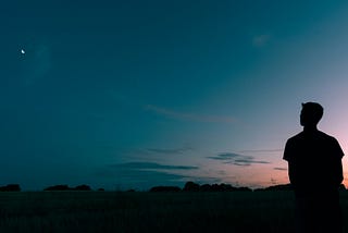A man sitting and thinking in nature while it is sunset