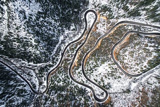 Overhead photo of a winding road through a snowy forest