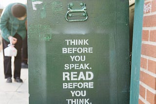 Dumpster bin with books on the top, with the quote on the side ‘Think before you speak, read before you think”