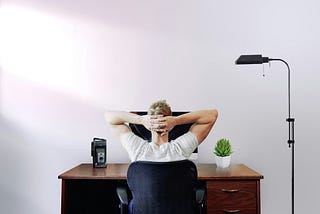 Man at laptop with hands behind head